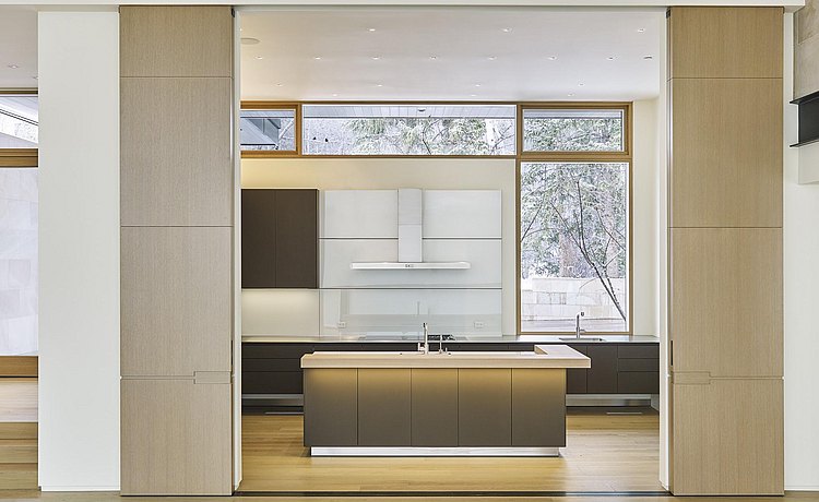 Dramatic view of large custom wood sliding doors looking into kitchen space.